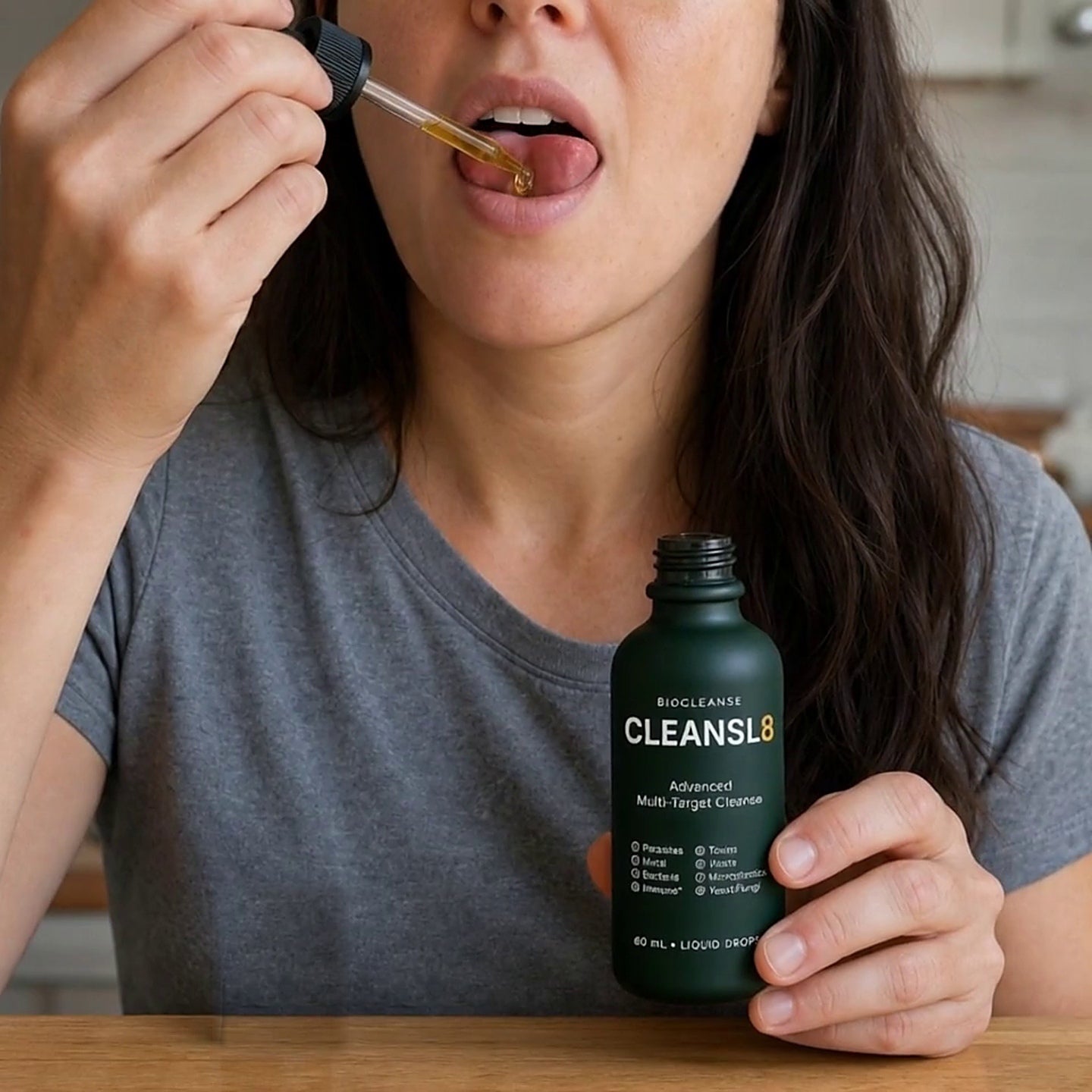 A woman taking CLEANSL8 drops under her tongue while holding the bottle